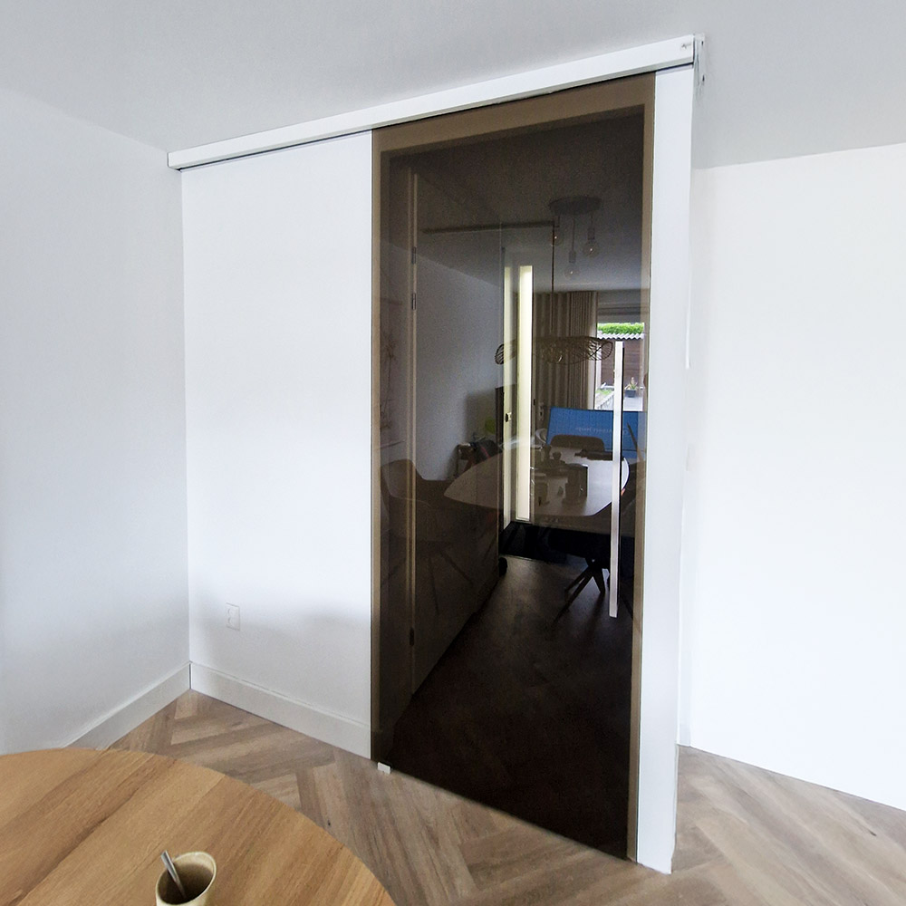 Brons getint glas in schuifdeur met mat wit glasbeslag en korte deurgreep